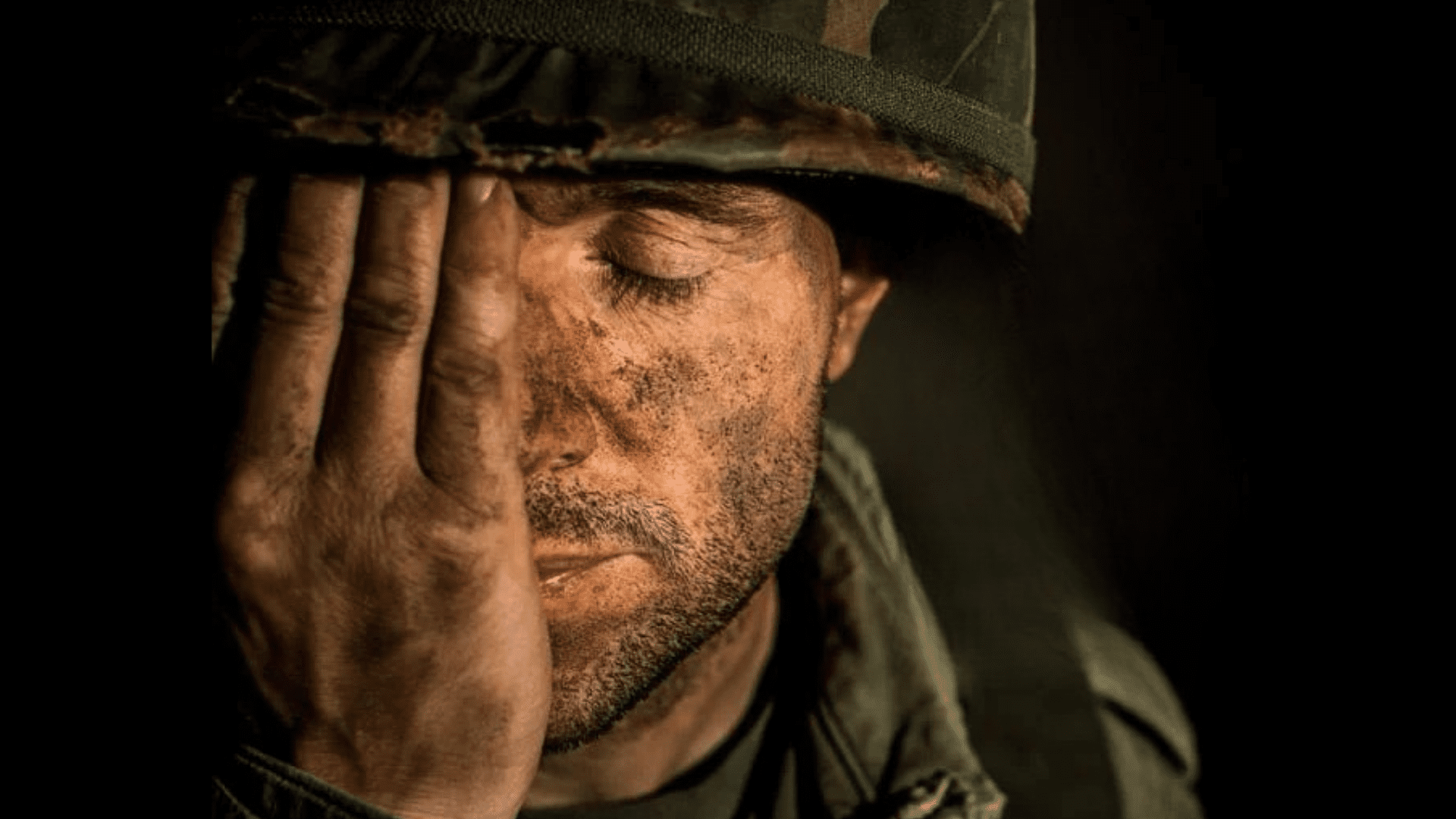 Soldier with dirt-covered face covering one eye
