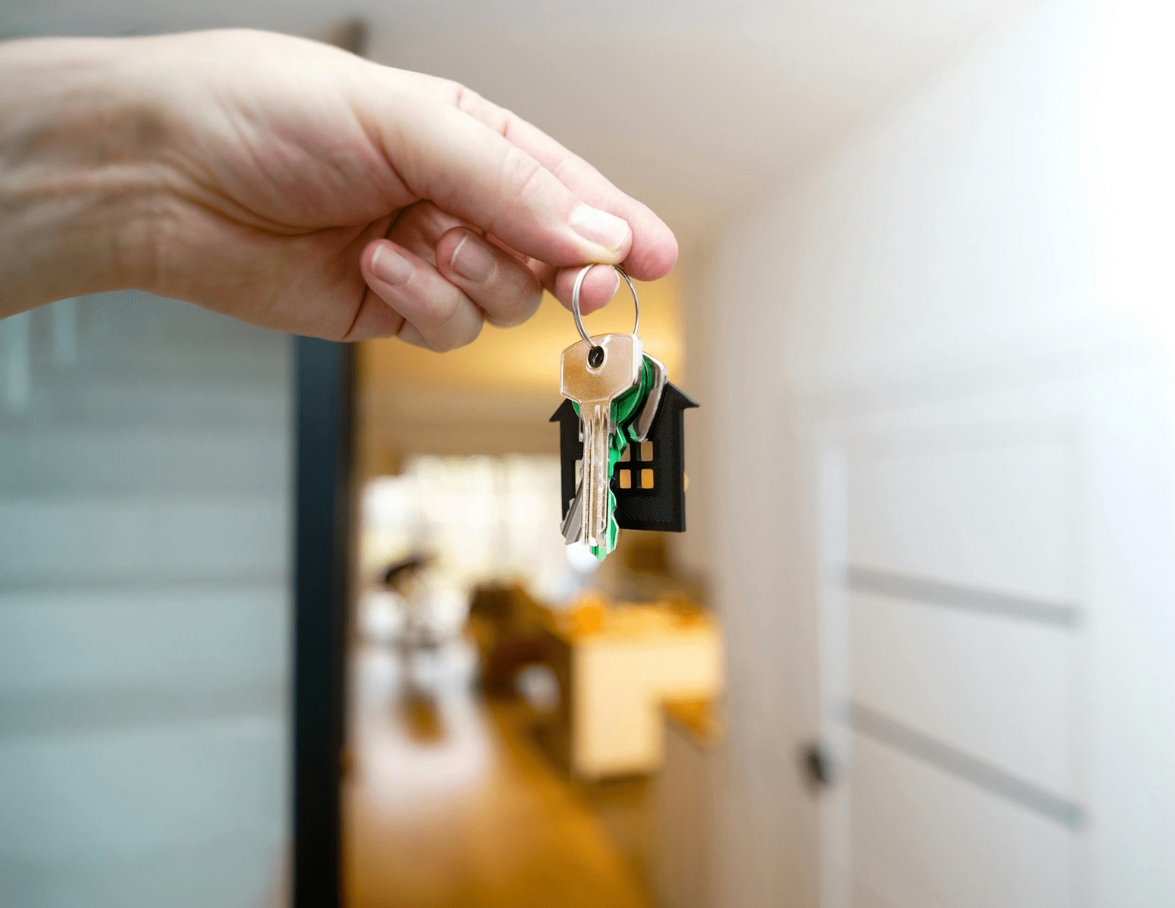 Hand holding house-shaped keychain with keys