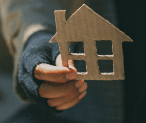 Hand holding cardboard house cutout